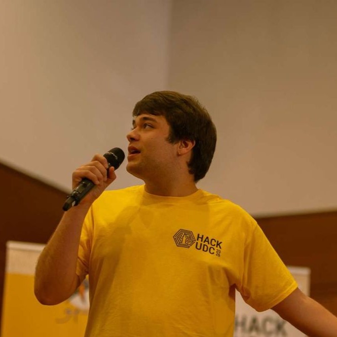 Alejandro Dopico on stage with a microphone at HackUDC